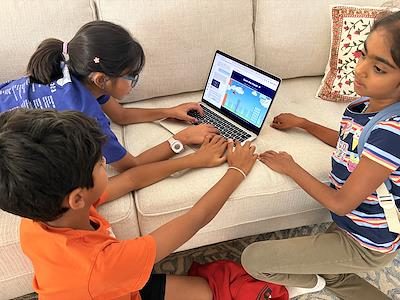 Three campers building around a laptop