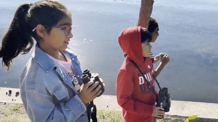 Campers holding binoculars at the lake