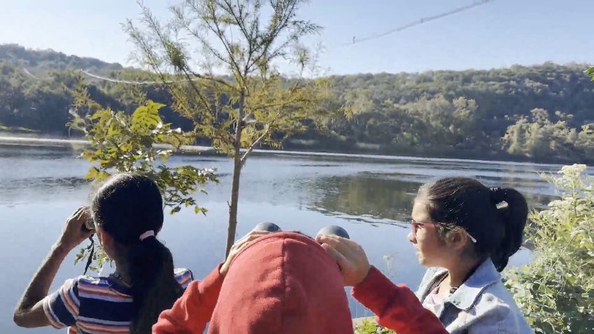 Campers birding at the lake with wooded hills across the water
